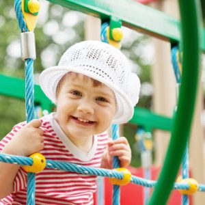 Enfant souriant jouant sur une structure de jeux en plein air