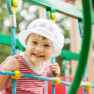 Enfant souriant jouant sur une structure de jeux en plein air