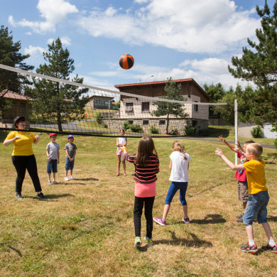 Groupe d’enfants jouant au volley-ball en plein air dans un village vacances