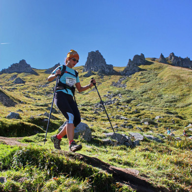 Femme participant à une course de trail en montagne avec bâtons de randonnée