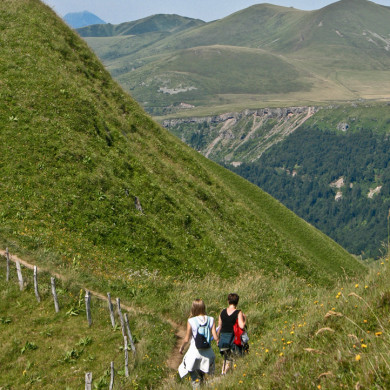 Randonneurs parcourant un sentier de montagne verdoyante en Auvergne