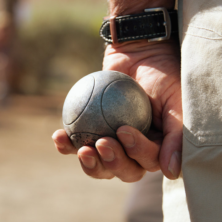 Main tenant une boule de pétanque prête à être lancée