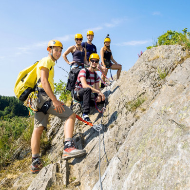 Groupe de vacanciers équipés de casques et baudriers sur un parcours de via ferrata