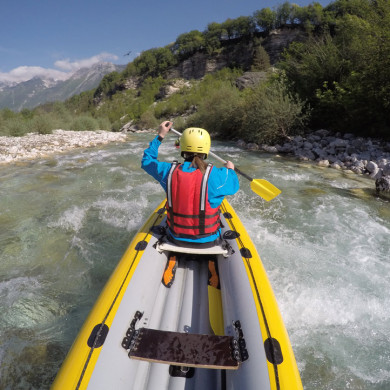 Personne en kayak descendant une rivière de montagne avec casque et gilet de sauvetage