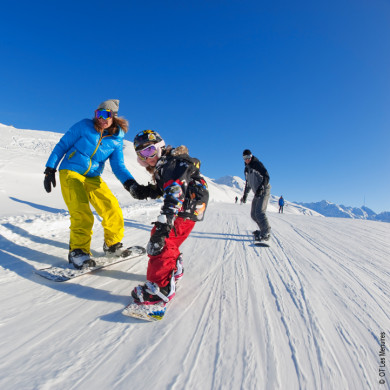 Famille avec enfants pratiquant le snowboard sur les pistes de ski