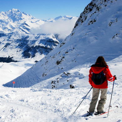 Skieuse admirant le panorama alpin enneigé depuis une piste de ski