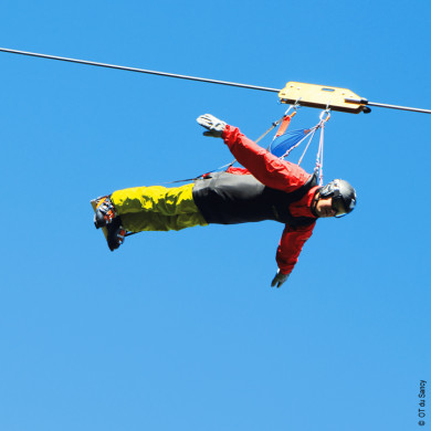 Personne pratiquant la tyrolienne à Murol en Auvergne sous un ciel bleu