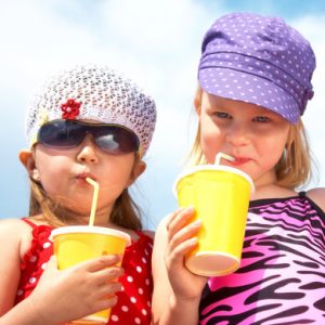 Deux petites filles en maillot de bain sirotant une boisson fraîche en vacances d’été