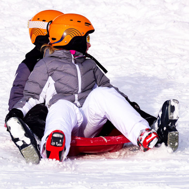 Enfants en luge sur la neige avec casque de protection à La Clusaz