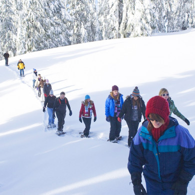 Groupe de vacanciers en randonnée raquettes dans la neige à Murol