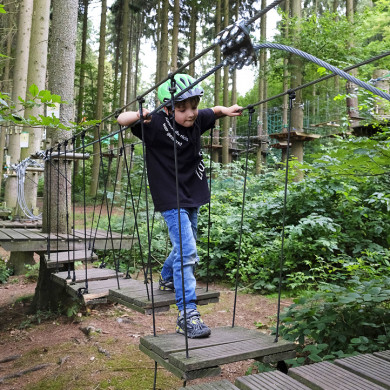 Enfant pratiquant l’accrobranche dans une forêt à Piau-Engaly