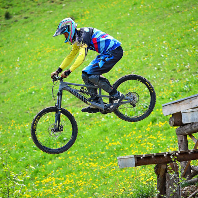 Sportif en VTT de descente franchissant un saut à Metabief en montagne