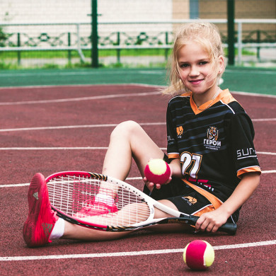 Petite fille souriante jouant au tennis sur un terrain à Metabief