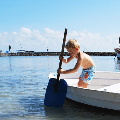 Enfant jouant sur un bateau au bord de la mer à Hauteville-sur-Mer
