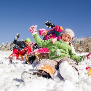 Enfants jouant à la luge et s’amusant dans la neige en famille