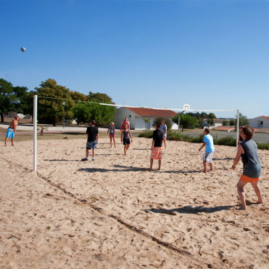Groupe de jeunes jouant au volley sur un terrain de sable en vacances