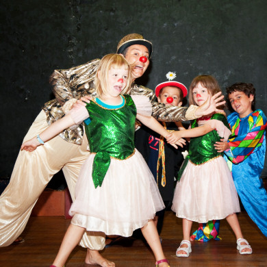 Clown et enfants déguisés en costumes colorés lors d’un spectacle de vacances
