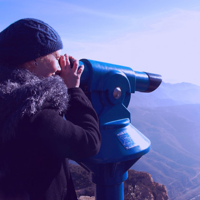 Femme observant le panorama montagneux avec une longue-vue touristique