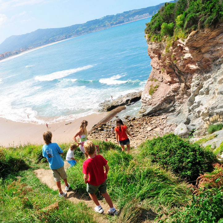 Famille en randonnée sur un sentier côtier avec vue sur l’océan Atlantique et plage du Pays Basque