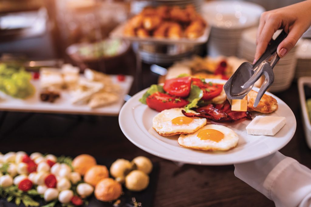 Assiette de petit-déjeuner avec œufs au plat, bacon, légumes frais et fromage au buffet Azureva