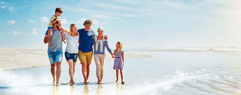 Famille multigénérationnelle en vacances marchant sur la plage au bord de la mer